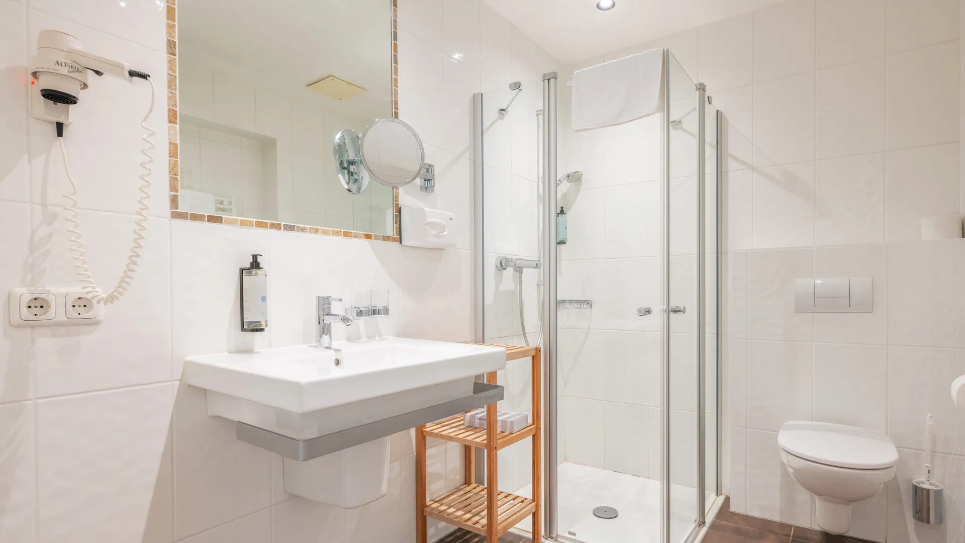 Badezimmer mit Dusche, Kosmetikspiegel und Haarfön