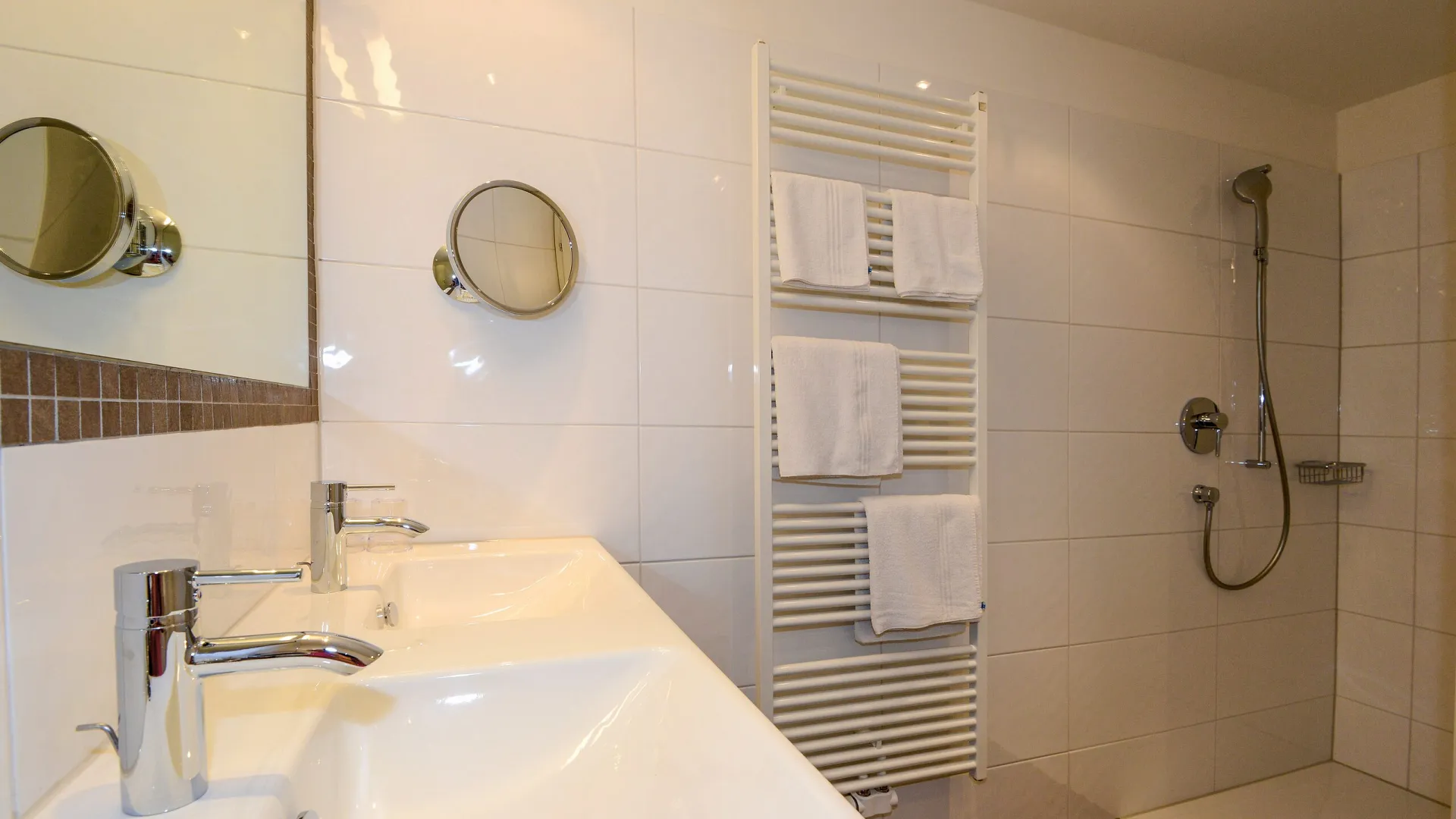 Badezimmer mit Walk-in-Dusche und Doppelwaschbecken im Familienzimmer Kalkstein