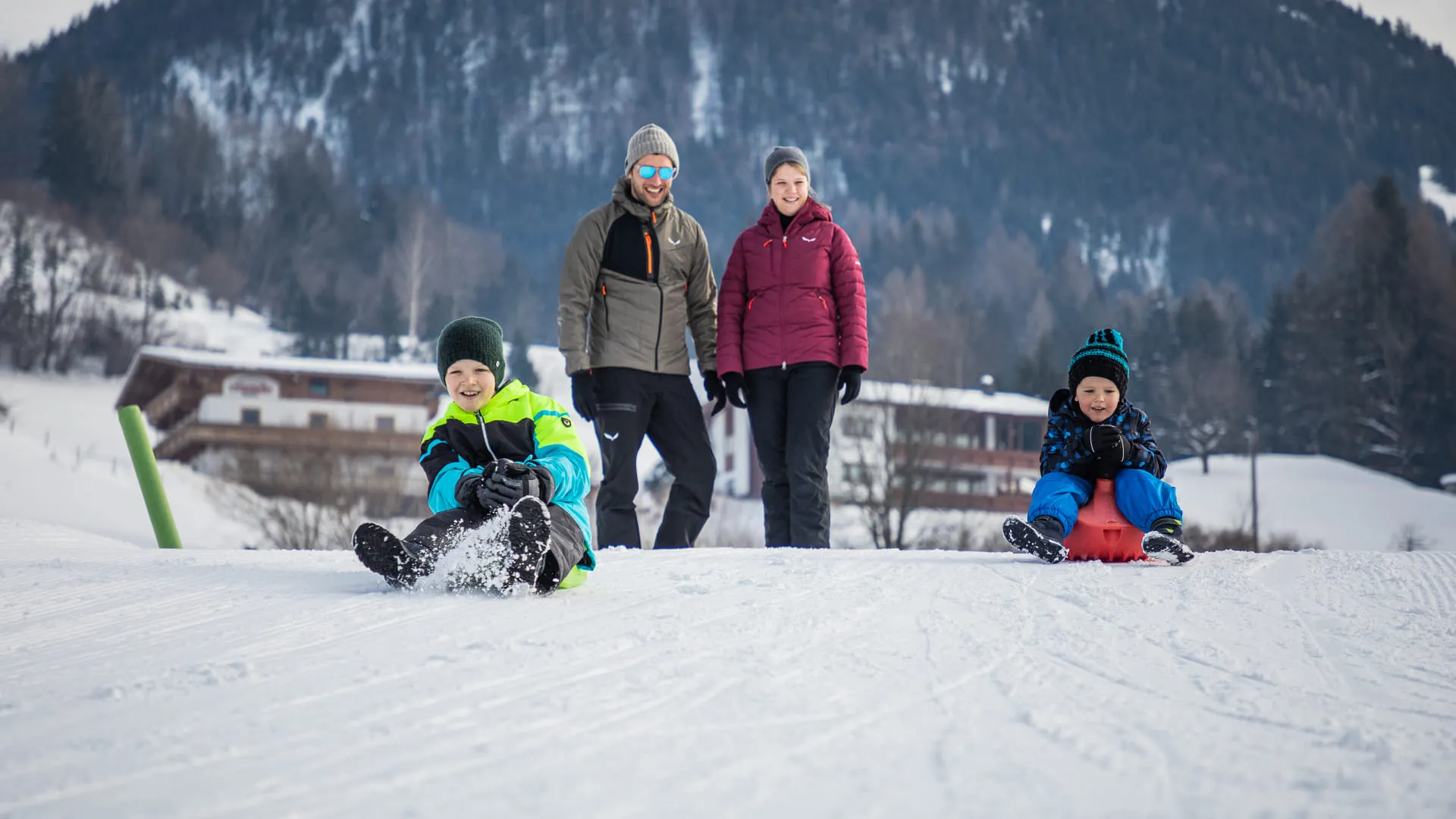 Familie beim Rodeln im Schnee